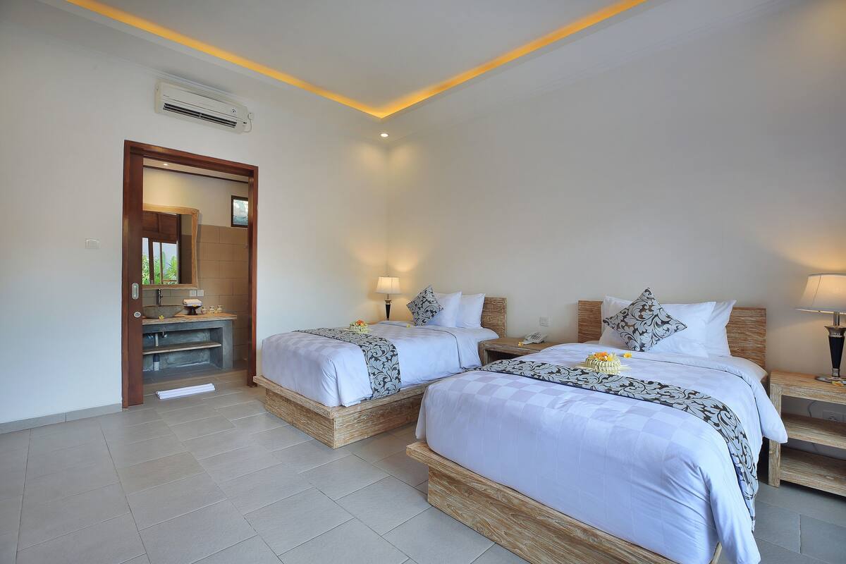 A hotel room with two beds, a bathroom, and a small sitting area.