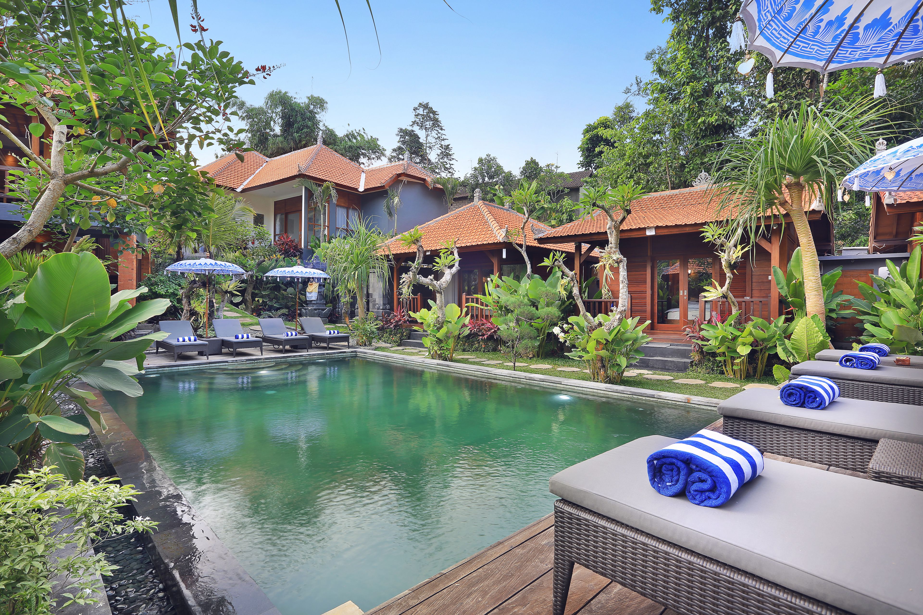 A poolside area with lounge chairs, a swimming pool, and overhanging umbrellas.