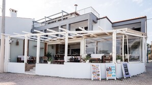 A modern outdoor cafe with a covered seating area, a menu board, and a view of the street.