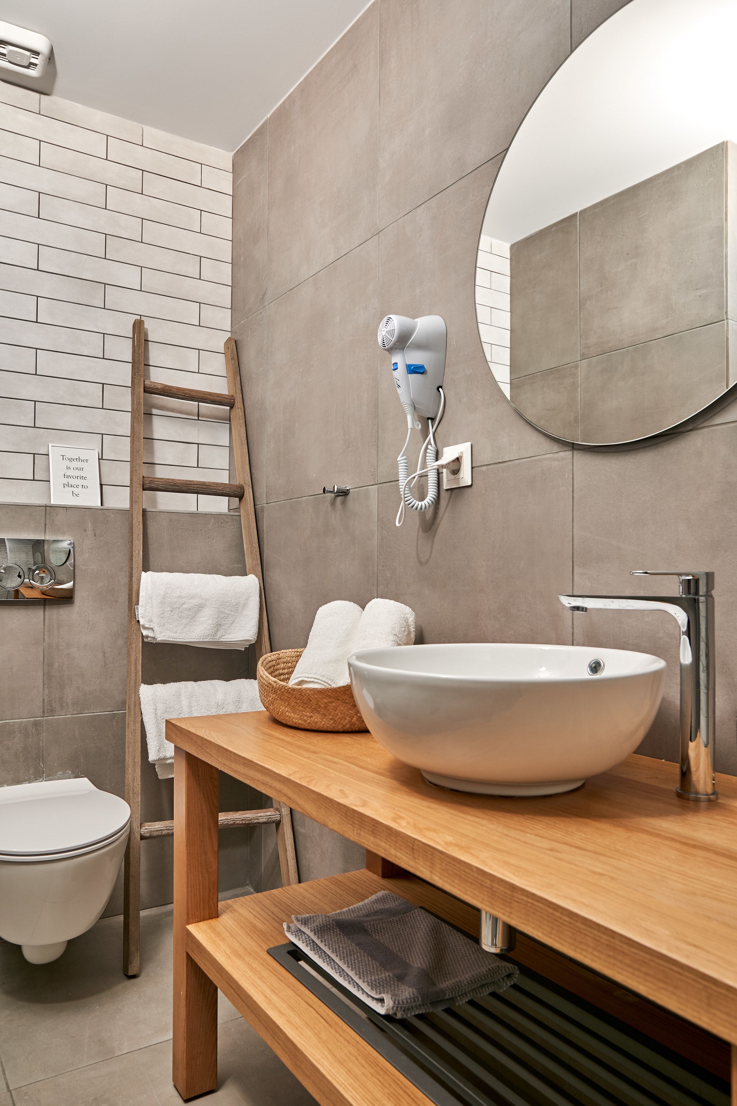 Un baño moderno con un lavamanos grande, un perchero, una escalera y un secador de pelo en la pared.