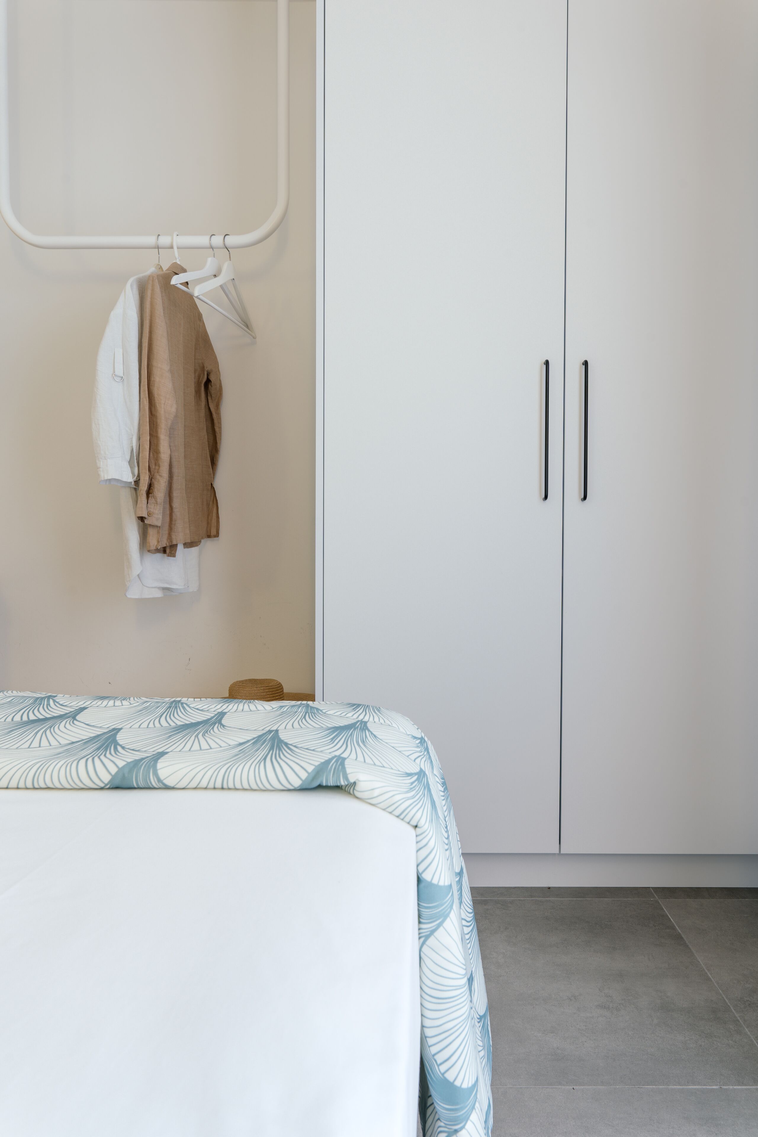Un dormitorio con cama, armario y perchero.