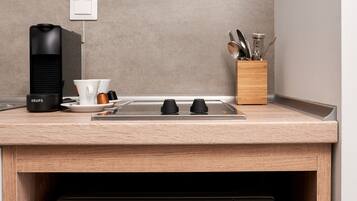 A compact kitchen with a built-in microwave and coffee maker, a wooden countertop, and a knife block.