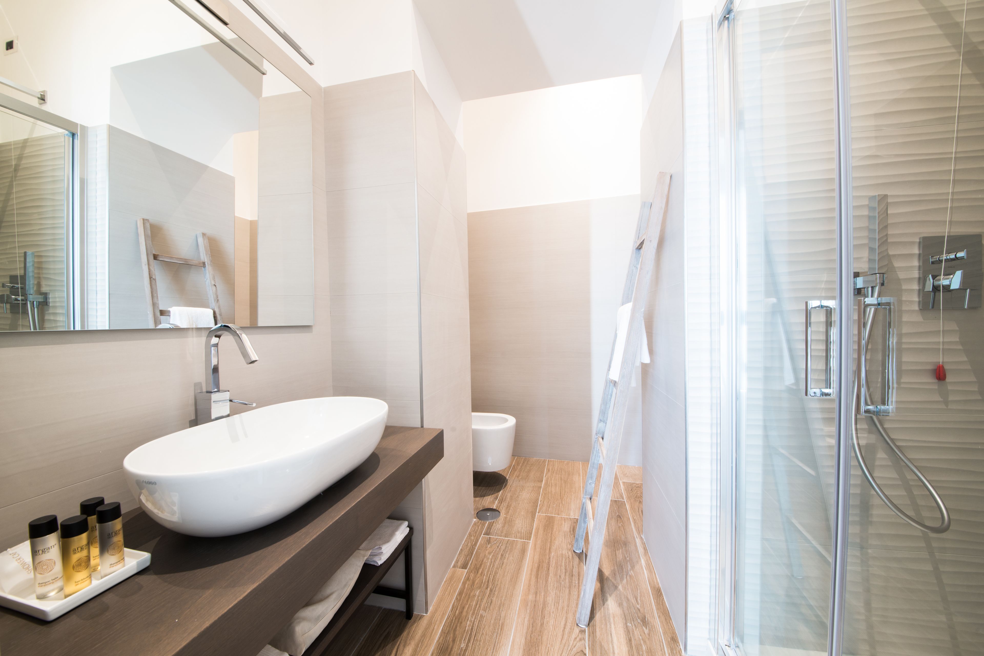 A modern bathroom with a large white sink, a mirror, and a glass shower enclosure.