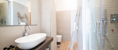 A modern bathroom with a large white sink, a mirror, and a glass shower enclosure.