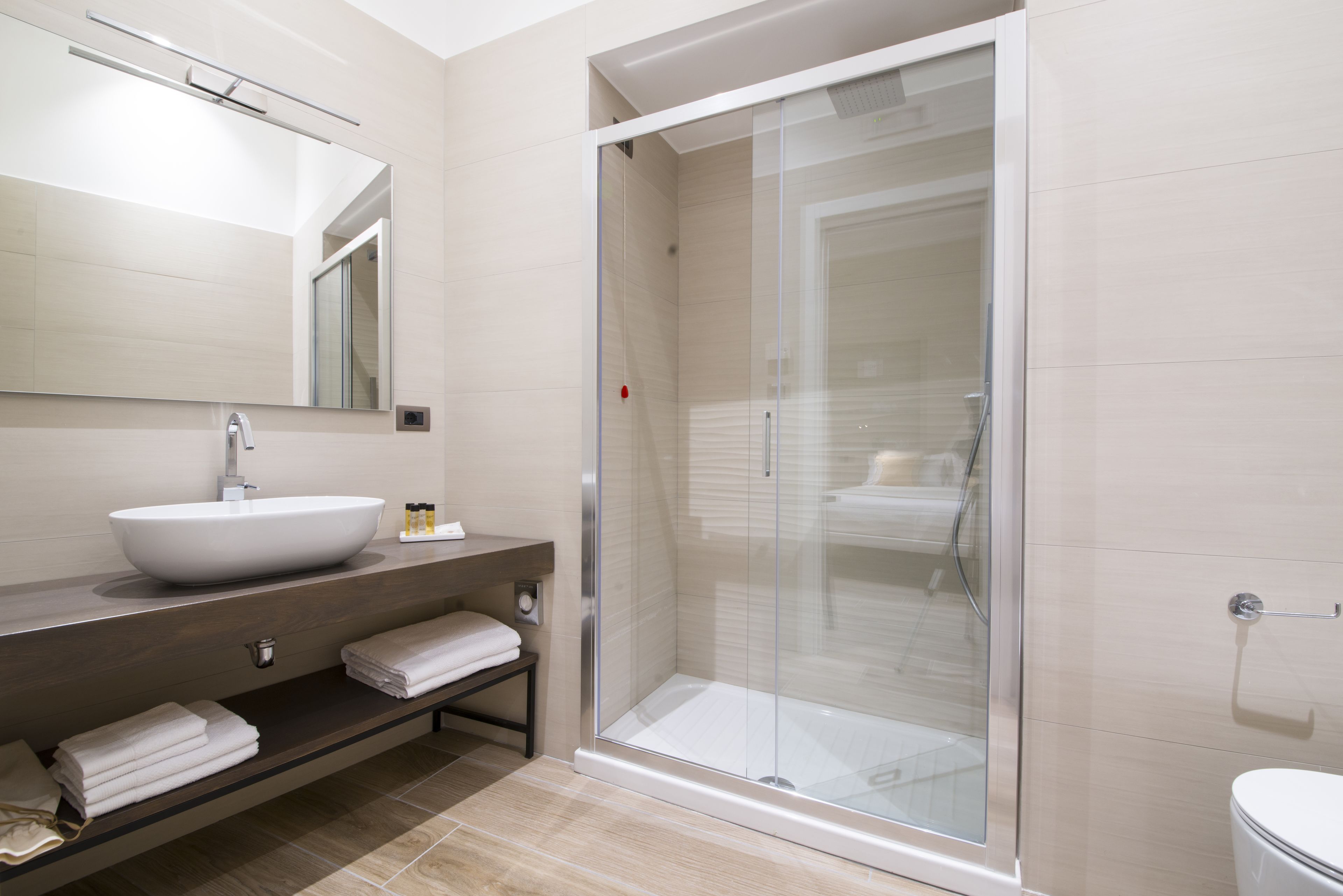 A modern bathroom with a large sink, a glass shower enclosure, and a toilet.