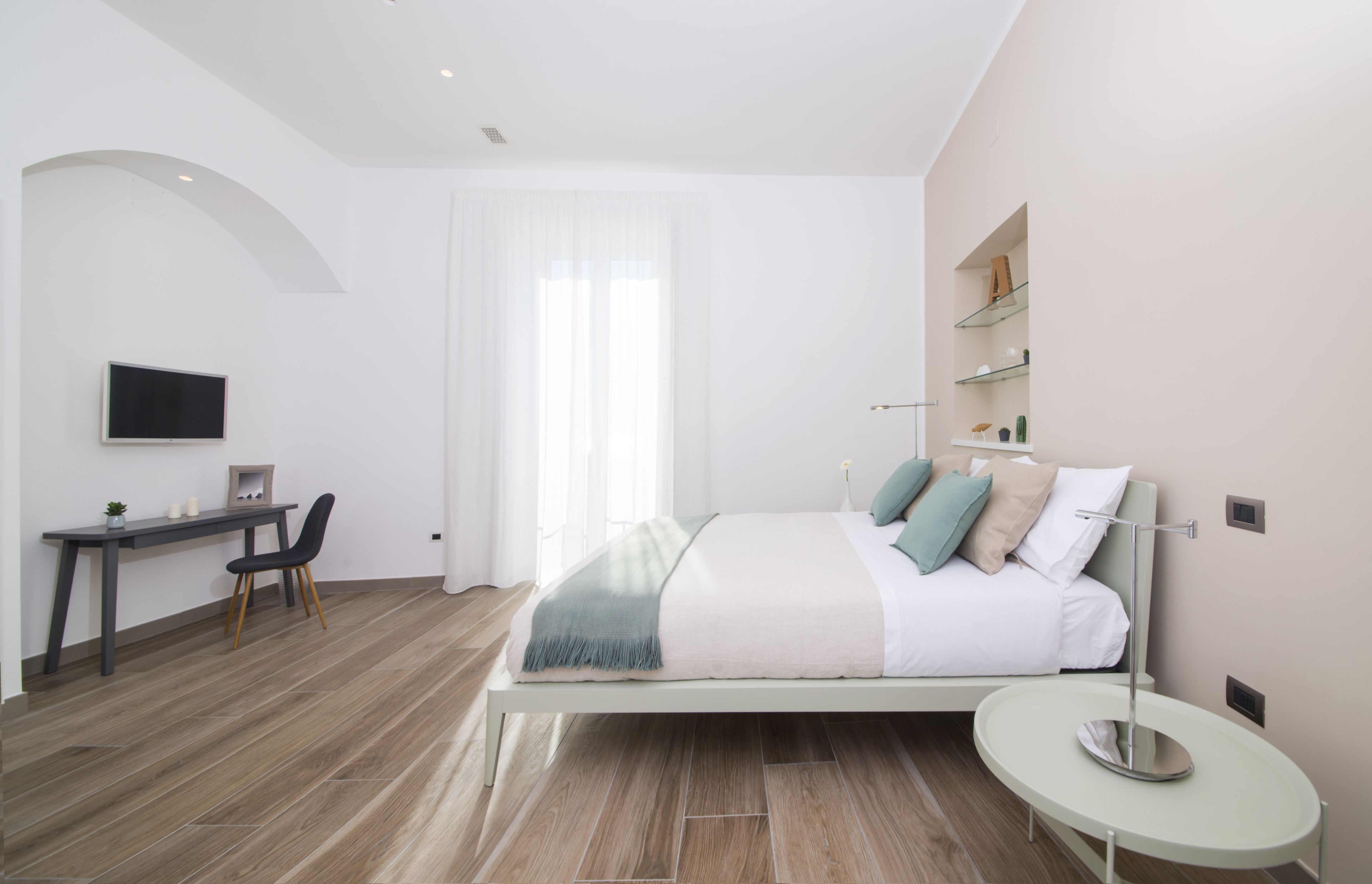 Una camera da letto moderna con un letto, un comodino e una scrivania con una sedia.