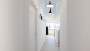 A modern hallway with white walls, a checkered floor, and a black refrigerator in the background. - AmbroSea Amalfi Coast (Vietri sul Mare)