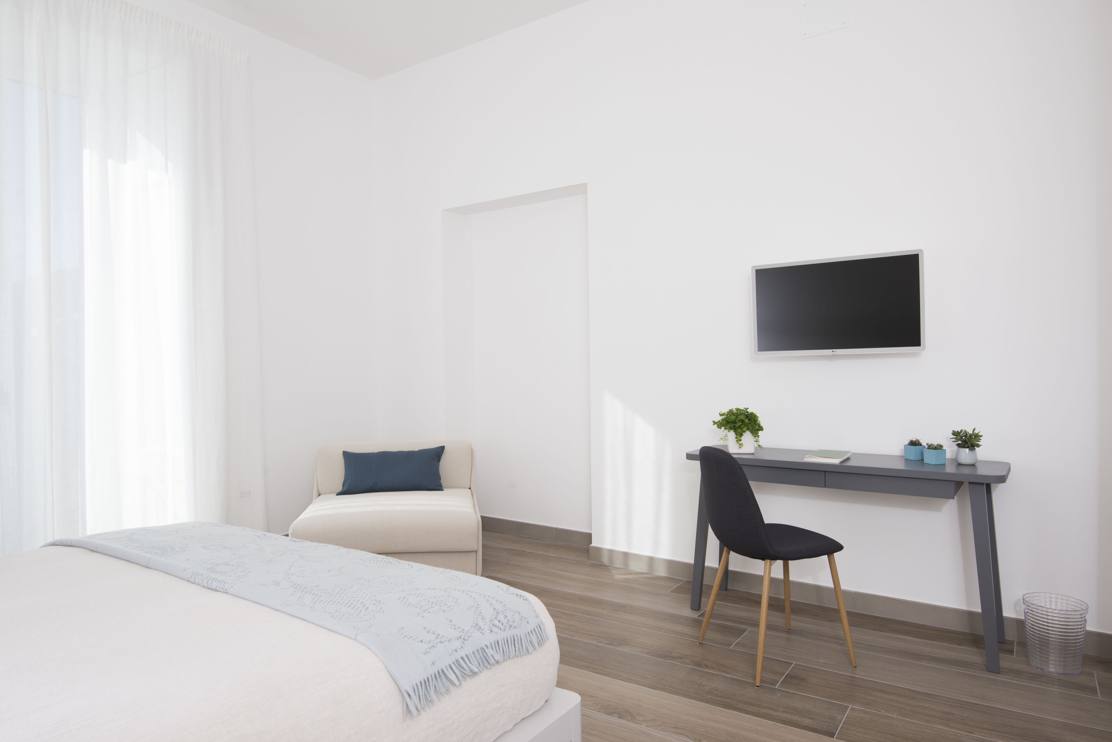 Un dormitorio moderno con una cama, un escritorio y una silla.