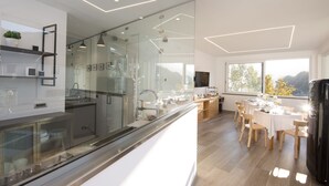 A modern kitchen with glass partitions, wooden cabinets, and a dining area with a view of the outdoors. - AmbroSea Amalfi Coast (Vietri sul Mare)