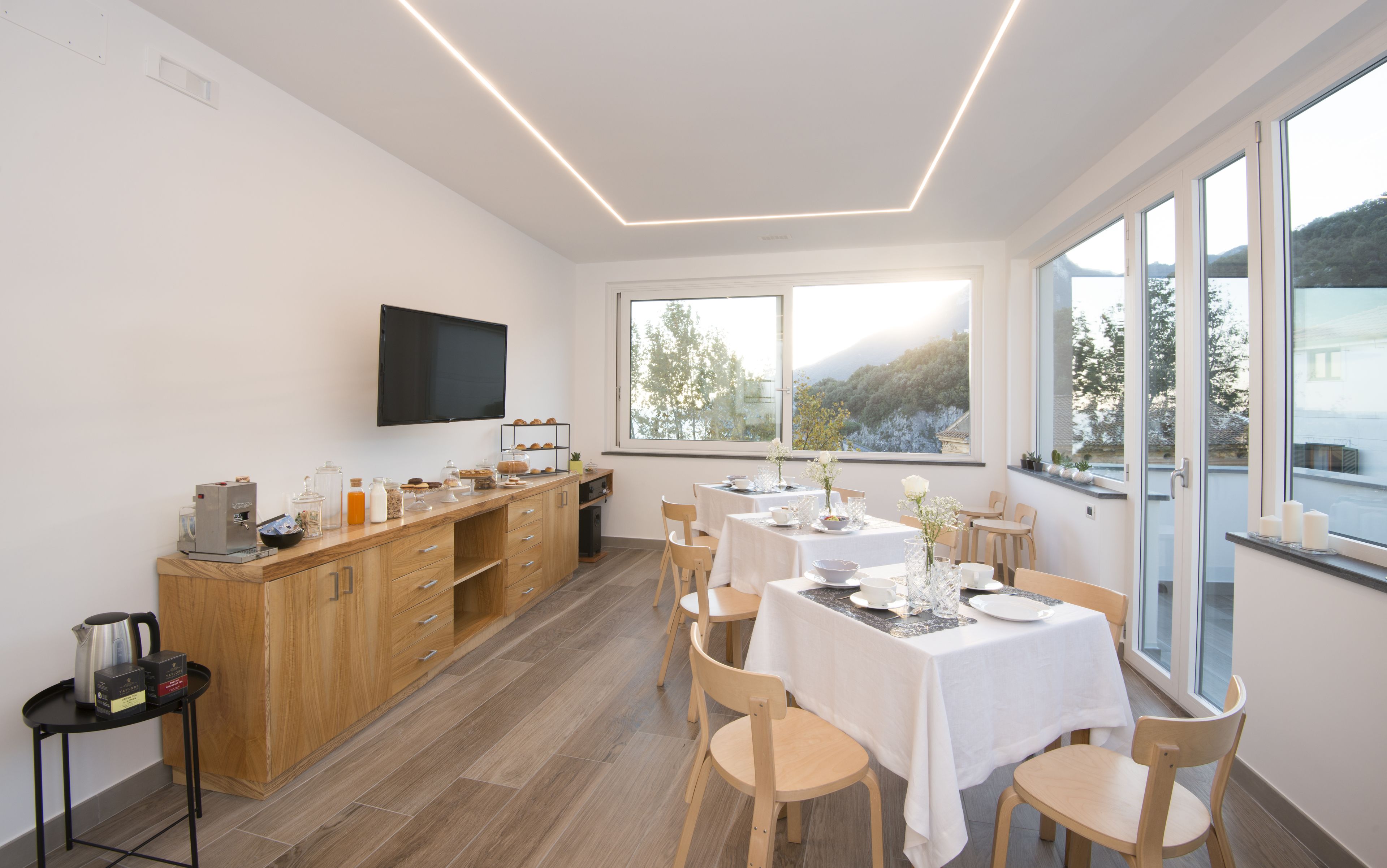 Un espace de repas moderne doté d’un comptoir de cuisine, d’un téléviseur à écran plat et de grandes fenêtres offrant une vue panoramique.