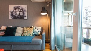 Un salon moderne avec un canapé gris, des coussins à motifs, un climatiseur fixé au mur et une lampe sur pied.