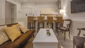 Een moderne woonkamer met een bruine bank, een witte salontafel en rieten stoelen.