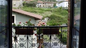 Ein Balkon mit schmiedeeisernen Geländern, der auf einen Wohnbereich mit Häusern und Grünflächen blickt.