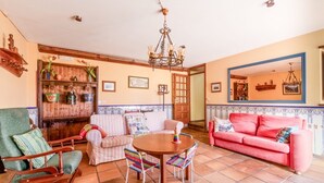 Ein gemütliches Wohnzimmer mit einem Holztisch, einem rosa Sofa und einem grünen Sessel.