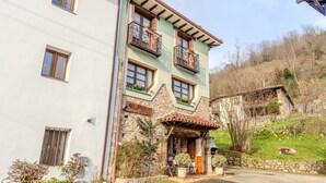 Ein mehrstöckiges Gebäude mit Balkonen, einer Steinaußenfassade und einem kleinen Garten.
