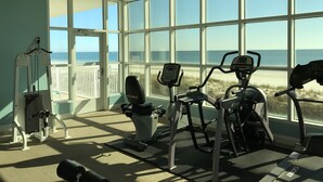 A gym with exercise equipment and large windows overlooking a beach. - Beachfront, East Corner Unit On The Tenth Floor With Huge Wrap Around Balcony (Gulf Shores)