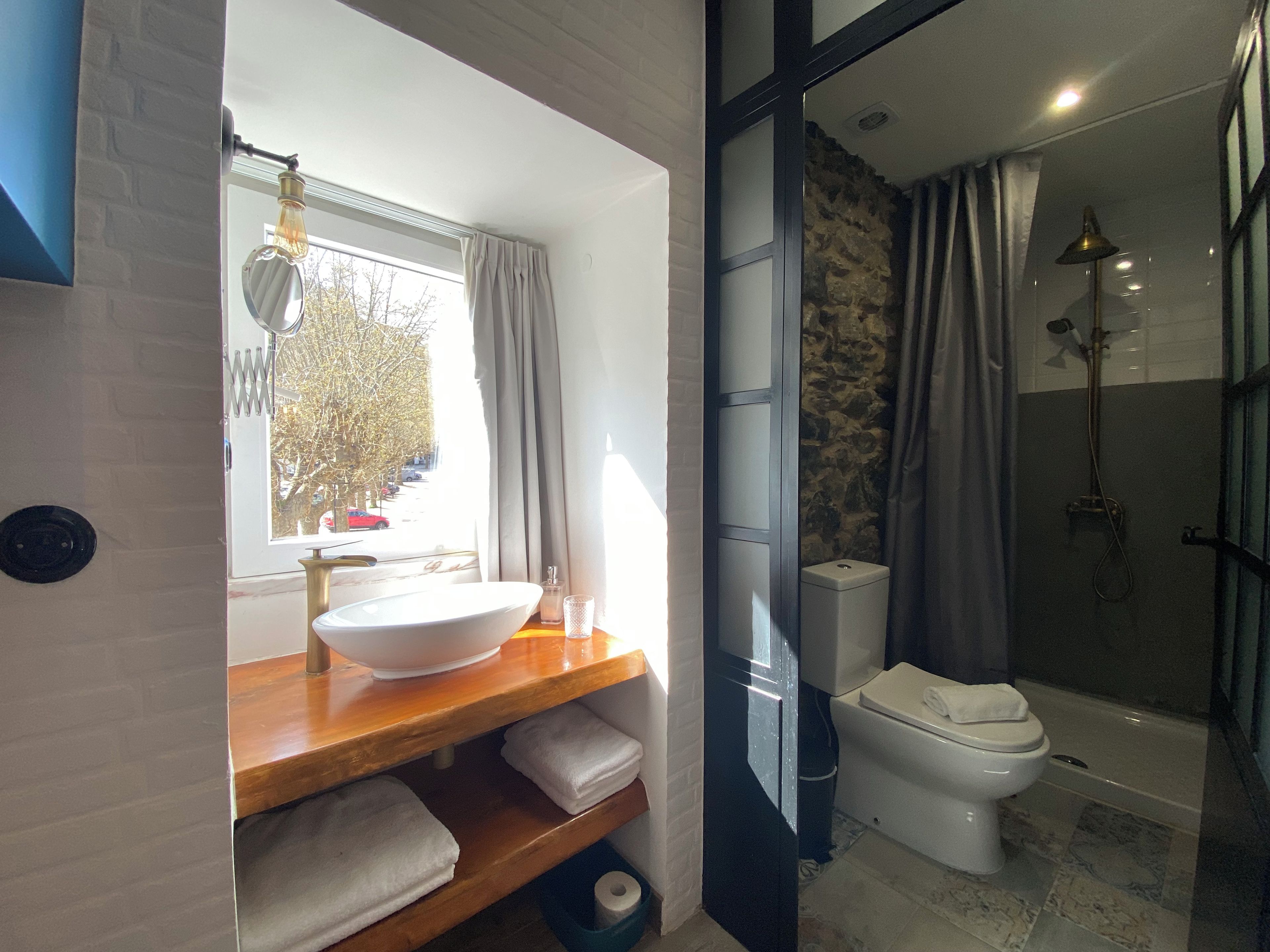 Une salle de bain dotée d’une grande fenêtre, d’un lavabo, de toilettes et d’un espace douche.