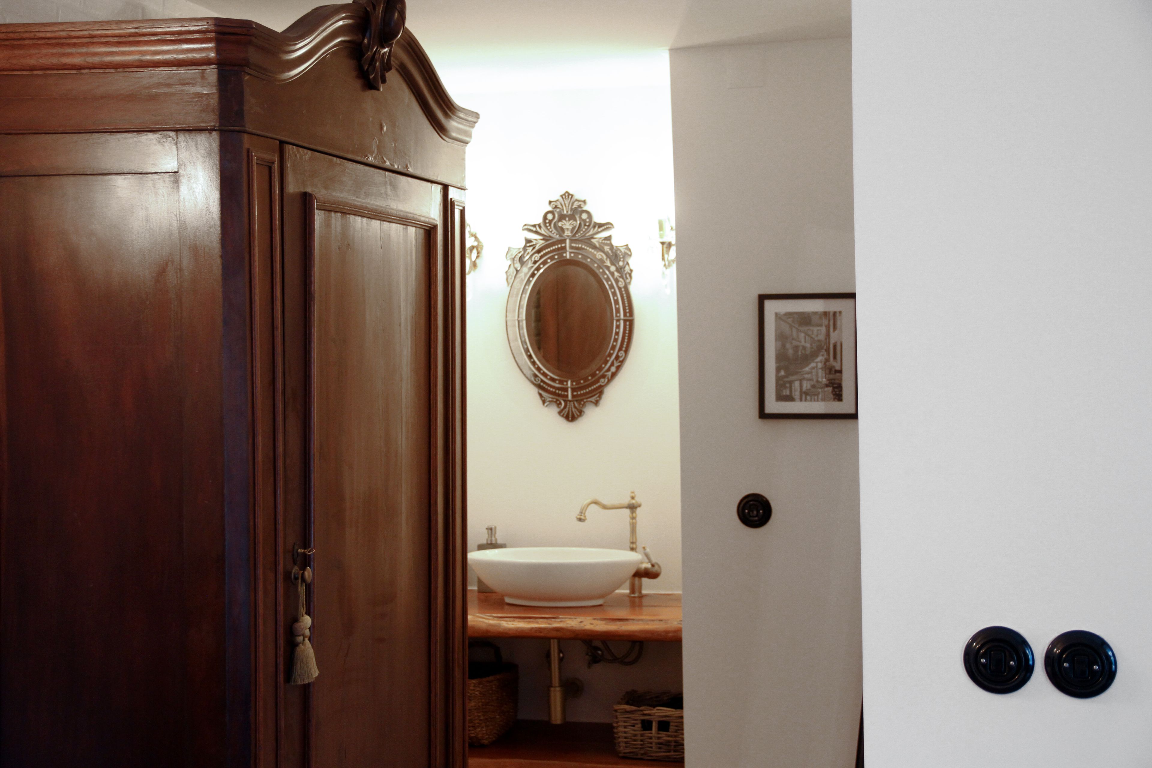 A wooden door leading to a bathroom with a white sink, a mirror, and a framed picture on the wall.