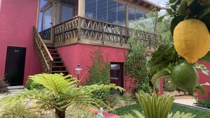 A two-story building with a red facade, large windows, and a wooden balcony. - Storytellers Villas (Sintra)