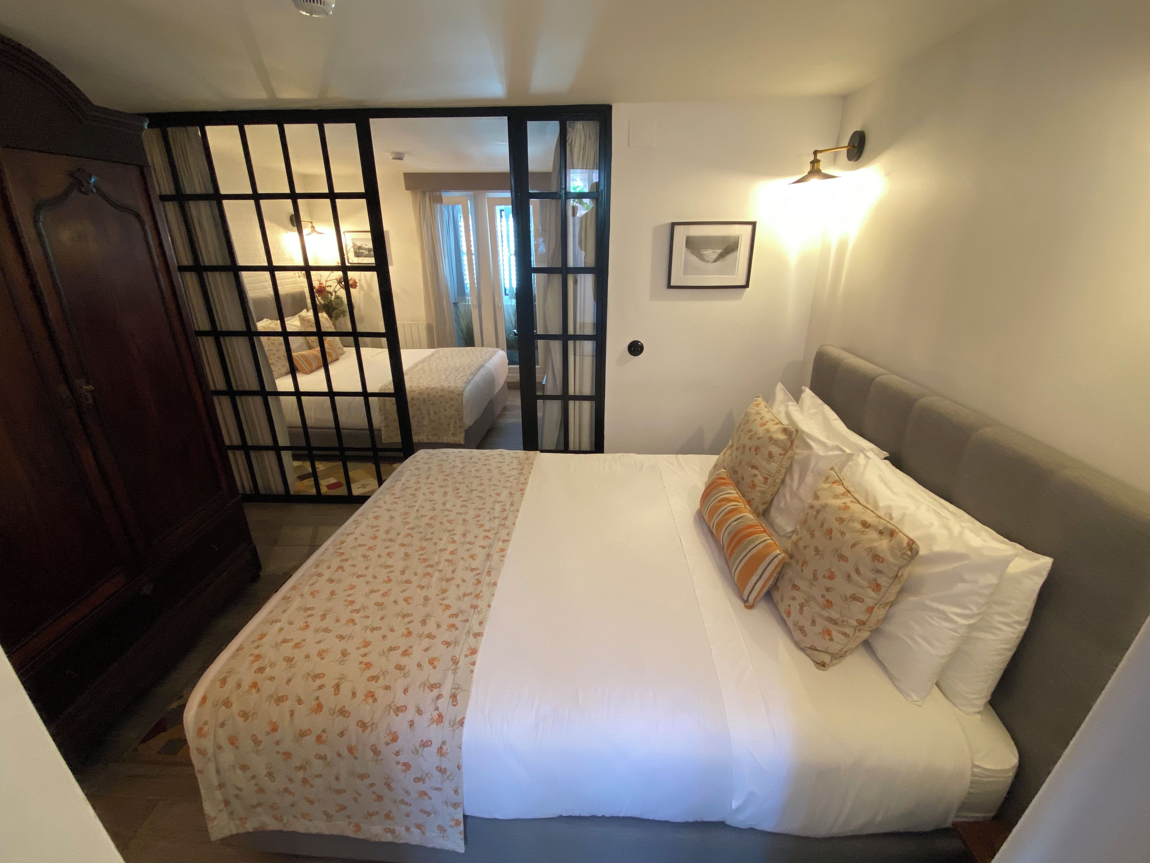Ein Schlafzimmer mit einem Bett, einem Kleiderschrank, einer Tür mit Fenster und einer Wandleuchte.