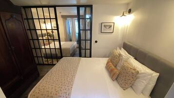 Ein Schlafzimmer mit einem Bett, einem Kleiderschrank, einer Tür mit Fenster und einer Wandleuchte.