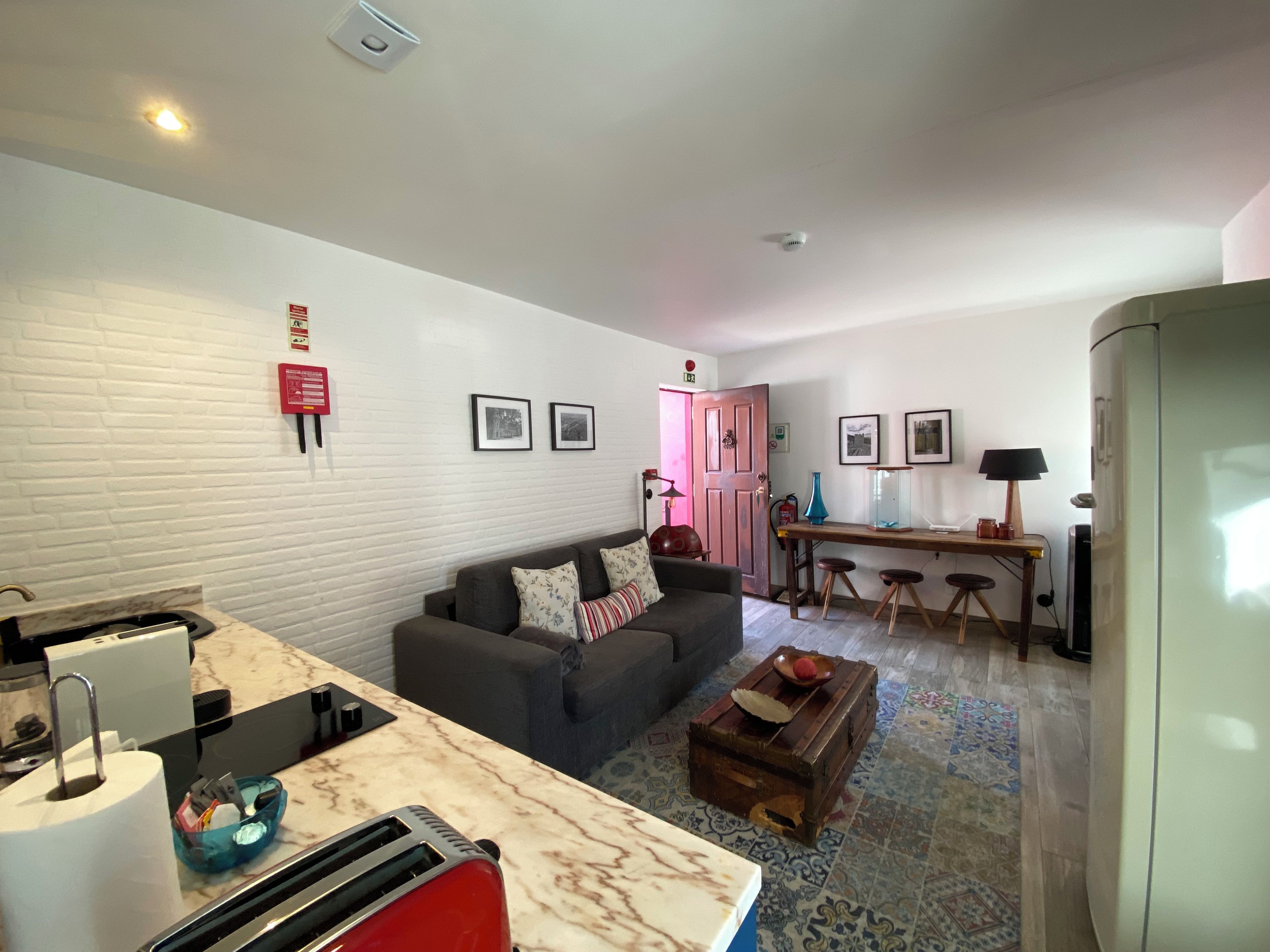 Un salon comprenant un canapé, une table basse, un coin repas avec une table et des chaises, et un coin cuisine avec un réfrigérateur.