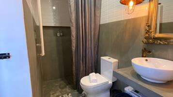 Een badkamer met toilet, wastafel, douchegordijn, vloertegels met patroon en een spiegel aan de muur.
