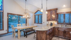 A spacious kitchen with a large island, wooden cabinets, and a dining area with a table and chairs. - Nice Home in Great Vail Location! Hot Tub, Free Shuttle Access!! (Vail)
