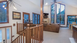 A spacious living area with a fireplace, large windows, and a wooden staircase. - Nice Home in Great Vail Location! Hot Tub, Free Shuttle Access!! (Vail)