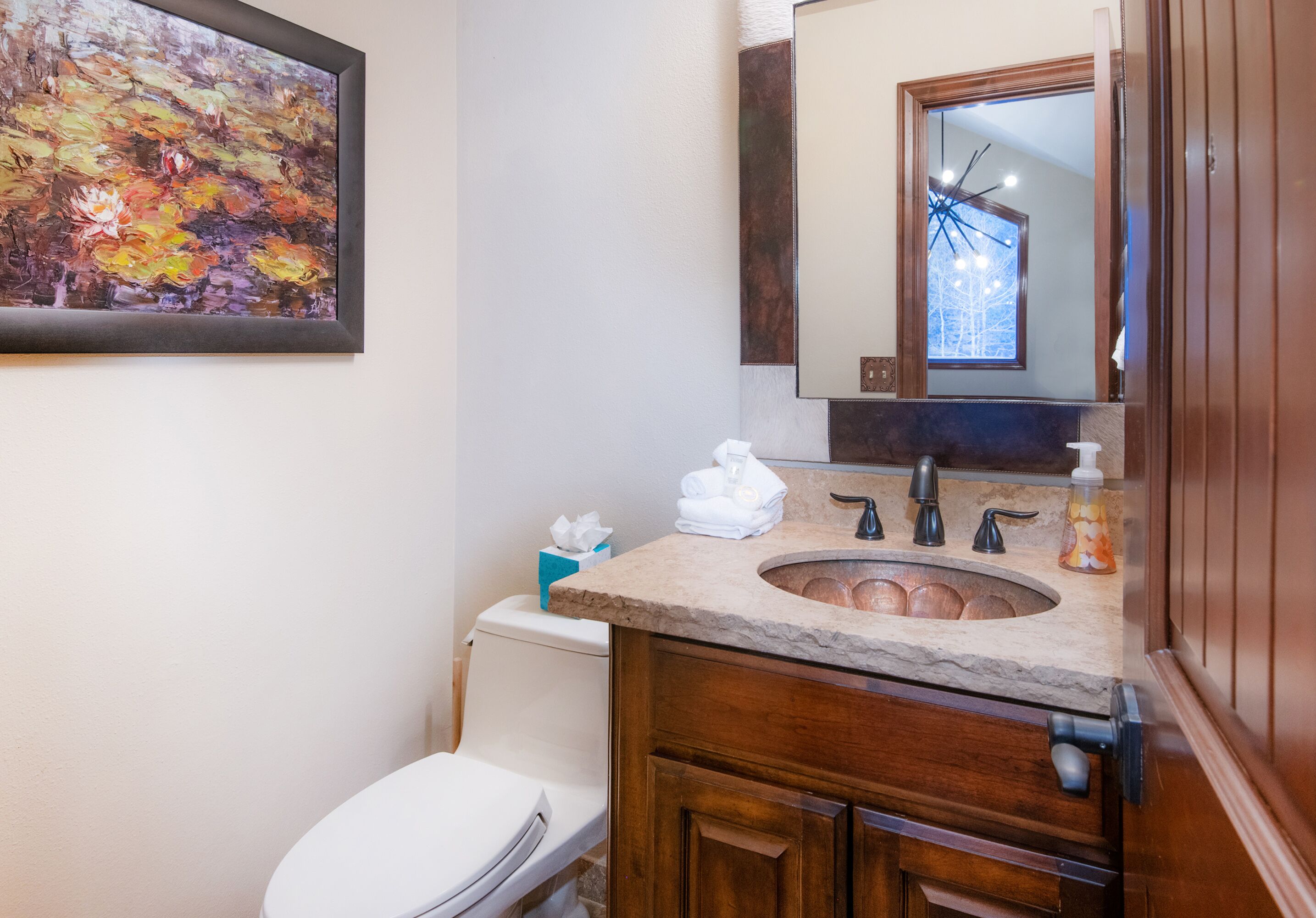 A bathroom with a marble sink, wooden vanity, and a large mirror.