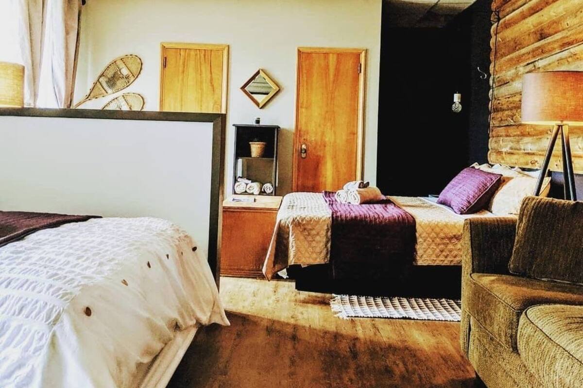 Ein Zimmer mit einem Bett, einem Schlafsofa, einem kleinen Tisch mit Lampe und einem Kleiderschrank.