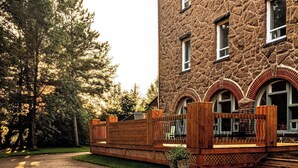 A stone building with a gravel driveway and wooden fence. - Maison Zacharie (Desbiens)