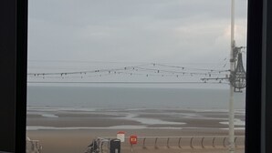 A beach view with a fence, a lifeguard tower, and power lines. - The Hotel Fame (Blackpool)