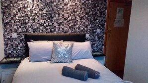 A hotel room with a bed, pillows, and a wall covered in photographs. - The Hotel Fame (Blackpool)