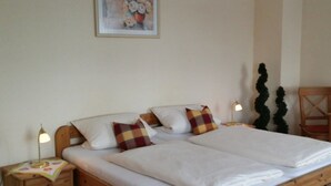 A double bed with white linens, two bedside tables with lamps, and a framed floral artwork on the wall. - Landgasthaus Hotel Zur Alten Linde (Hamersen)