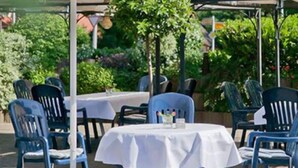 An outdoor patio with tables and chairs, surrounded by greenery and trees. - Landgasthaus Hotel Zur Alten Linde (Hamersen)