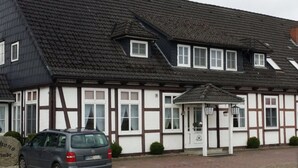 A traditional half-timbered building with a car parked in front. - Landgasthaus Hotel Zur Alten Linde (Hamersen)