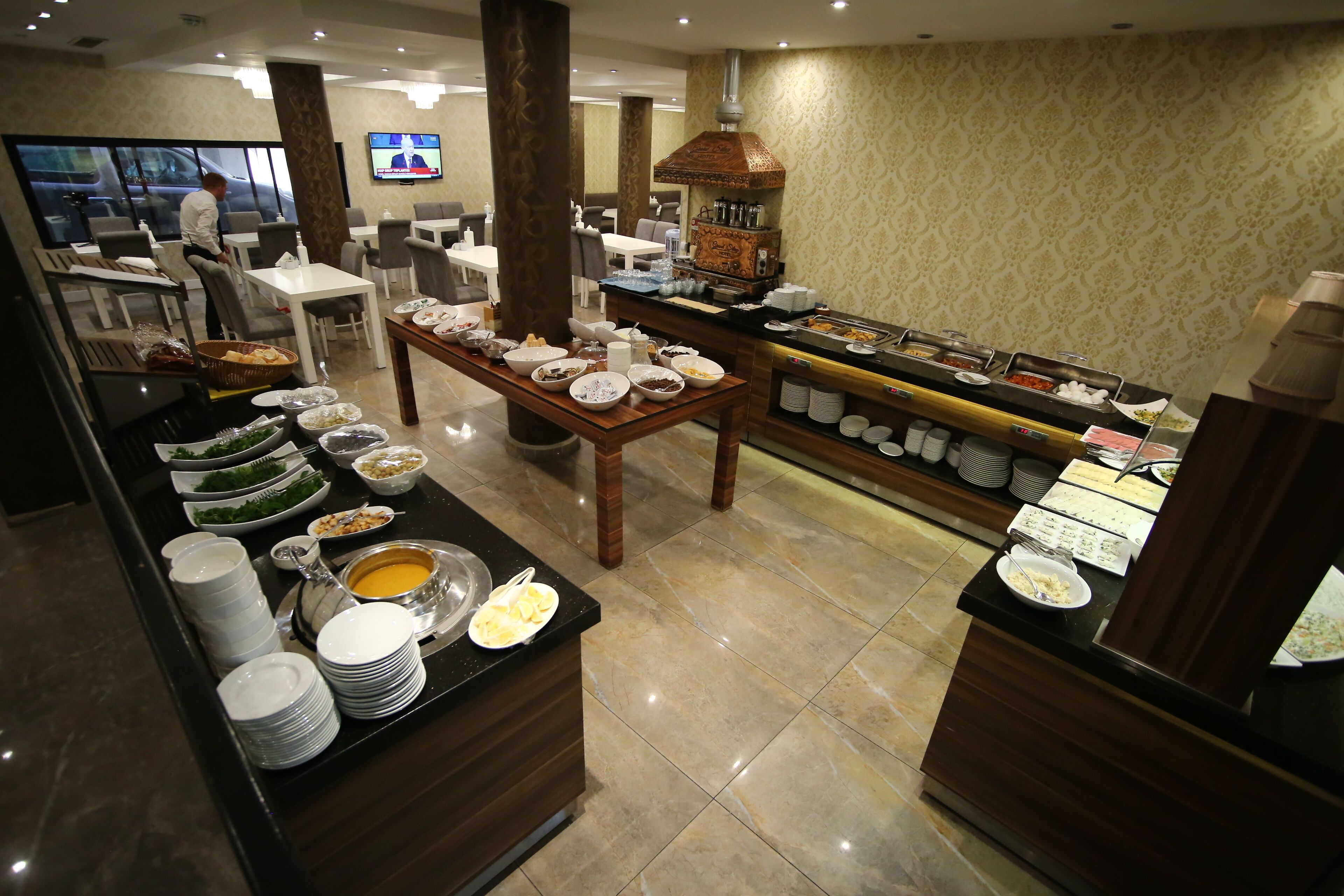 A buffet setup with various dishes and a television in the background.
