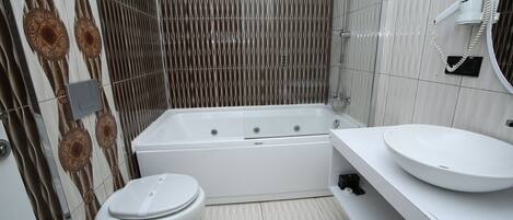 Un baño moderno con una bañera blanca, un inodoro y un lavabo con espejo.