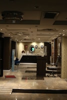 A reception area with a reception desk, a clock, and a wall-mounted display.