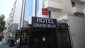 Un hotel chiamato "HOTEL GRAND SILAY" con una facciata moderna, ampie finestre e un cartello che indica la presenza di un bagno turco.
