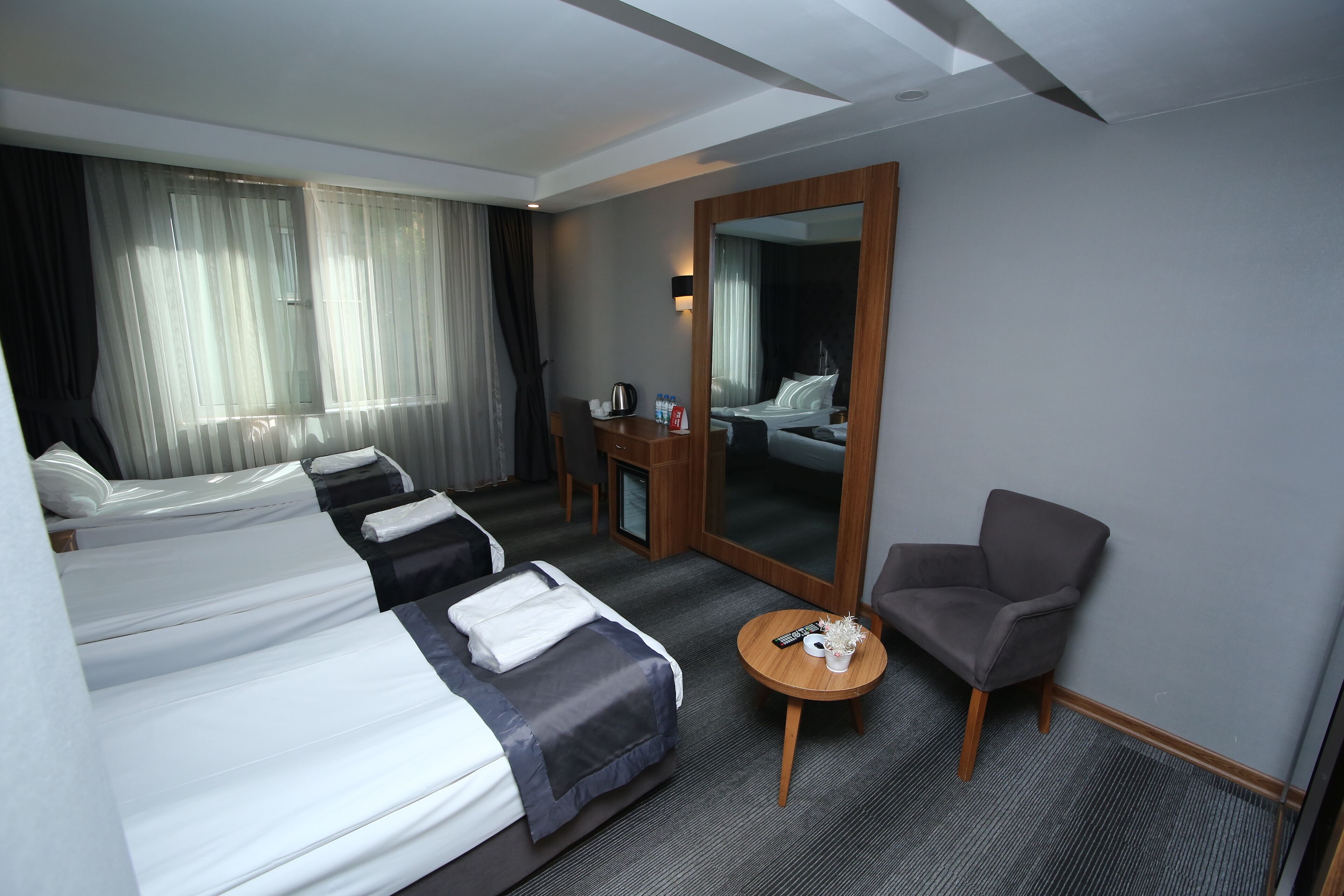 Una habitación de hotel con dos camas, un escritorio, una silla, una mesa redonda y un espejo grande.