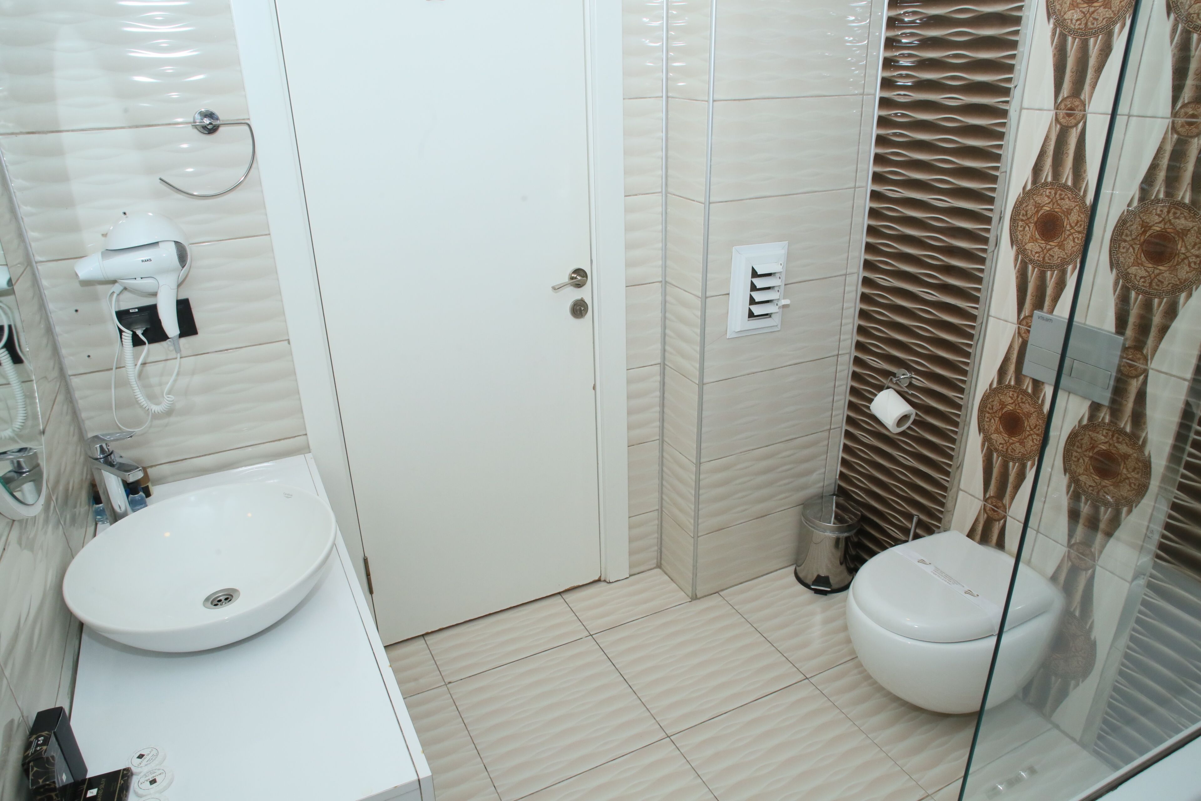 Un baño con lavamanos blanco, inodoro y zona de ducha.