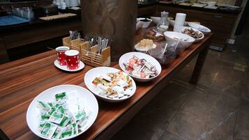 Disposição de buffet com diversos alimentos e utensílios.