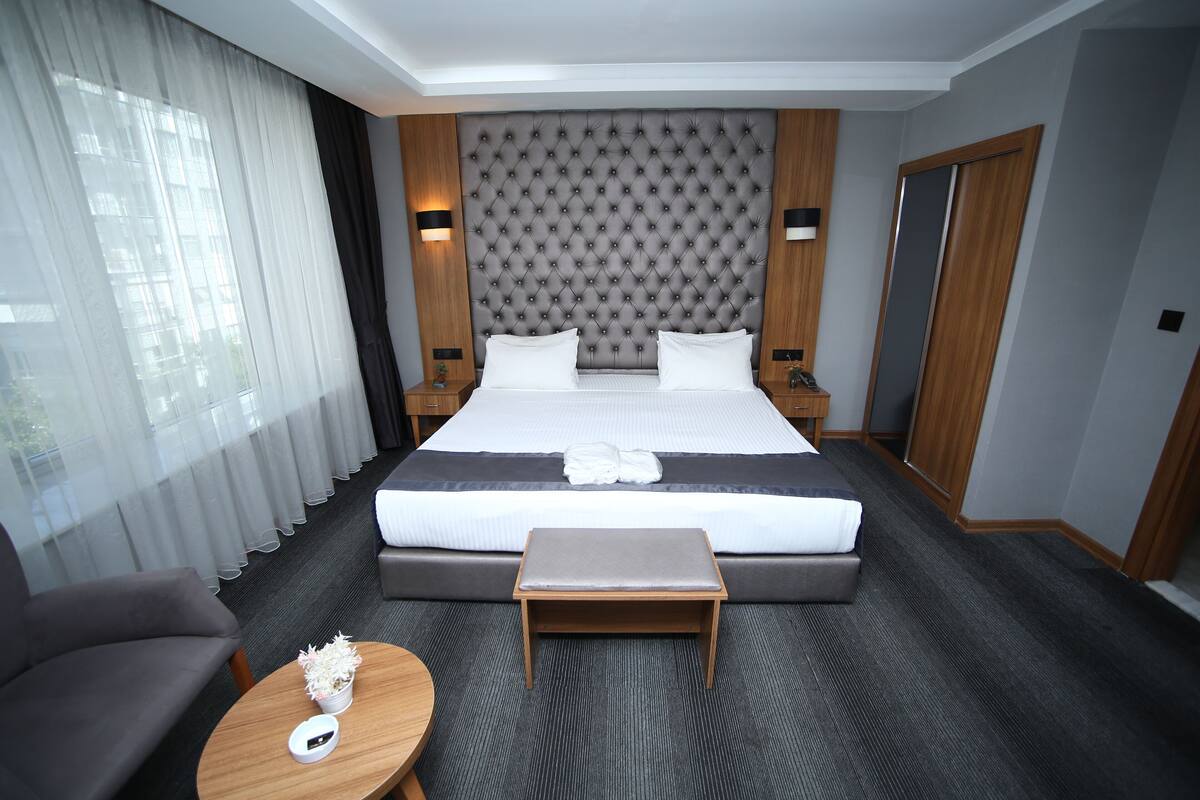 Una habitación de hotel con una cama grande, un sofá, una mesita y una mesita de noche.