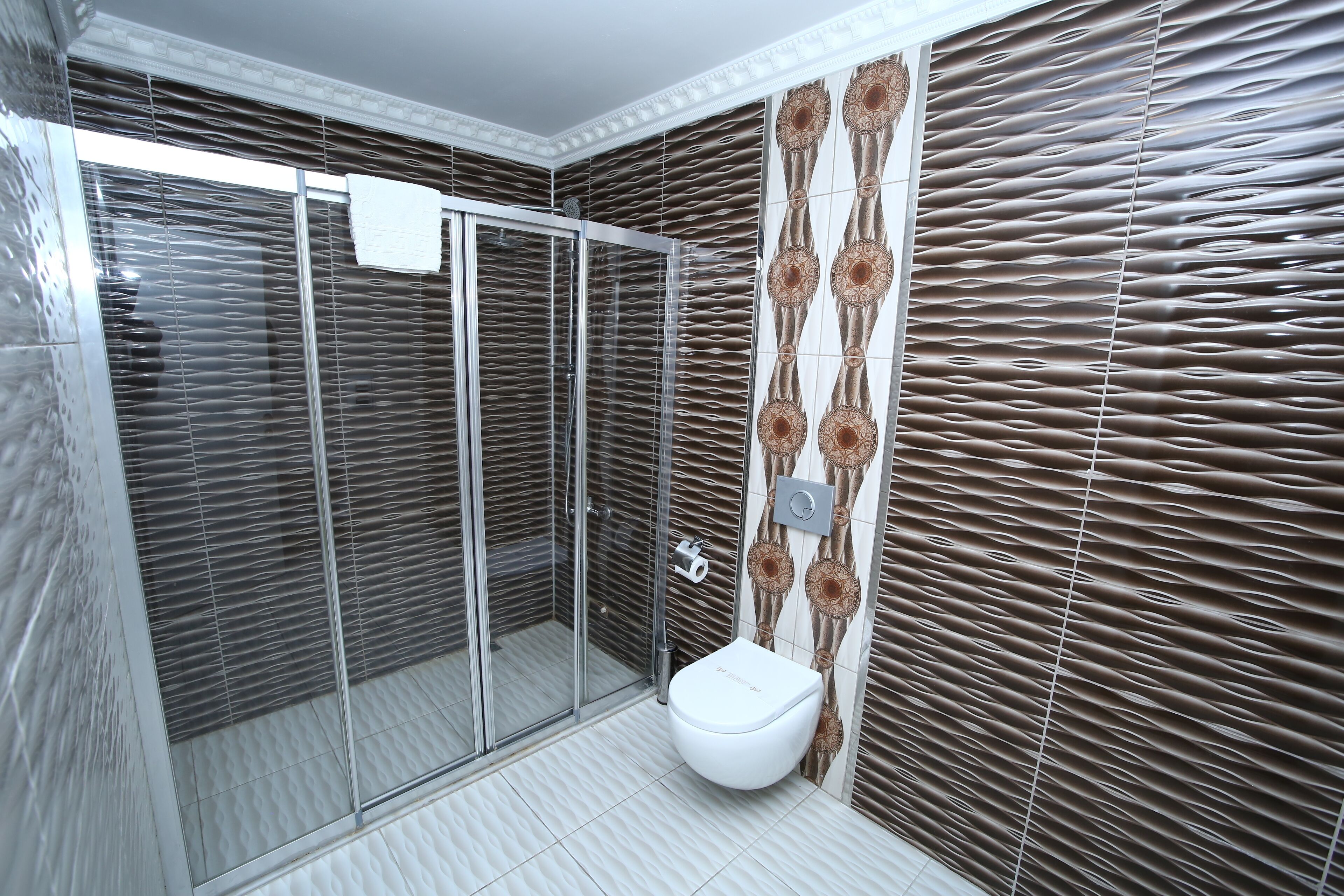 Un baño moderno con cabina de ducha de vidrio, un inodoro y azulejos con diseño.