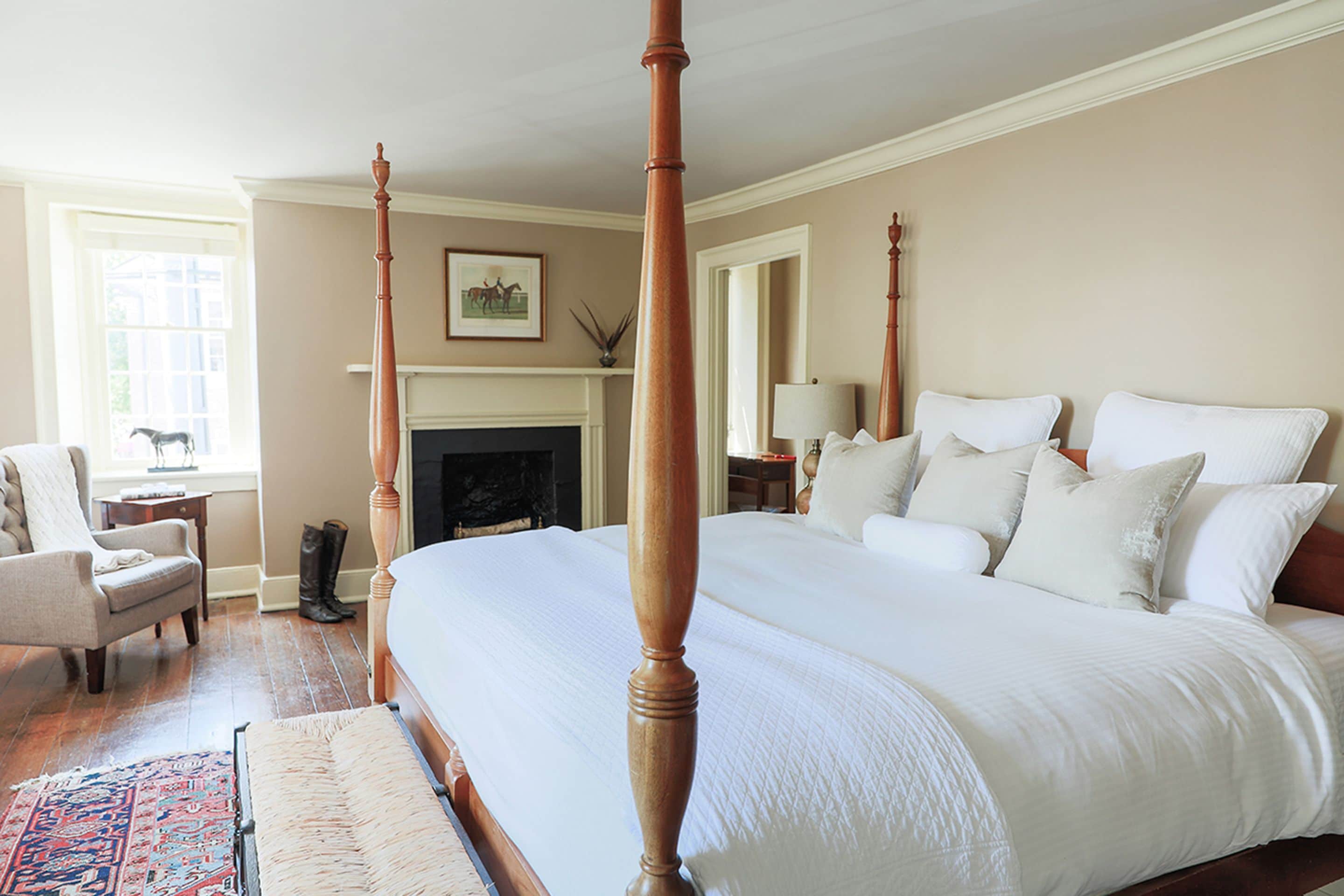 A spacious bedroom with a large bed, a chair, a fireplace, and a window.