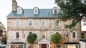 A stone building with a central entrance, multiple windows, and flags.