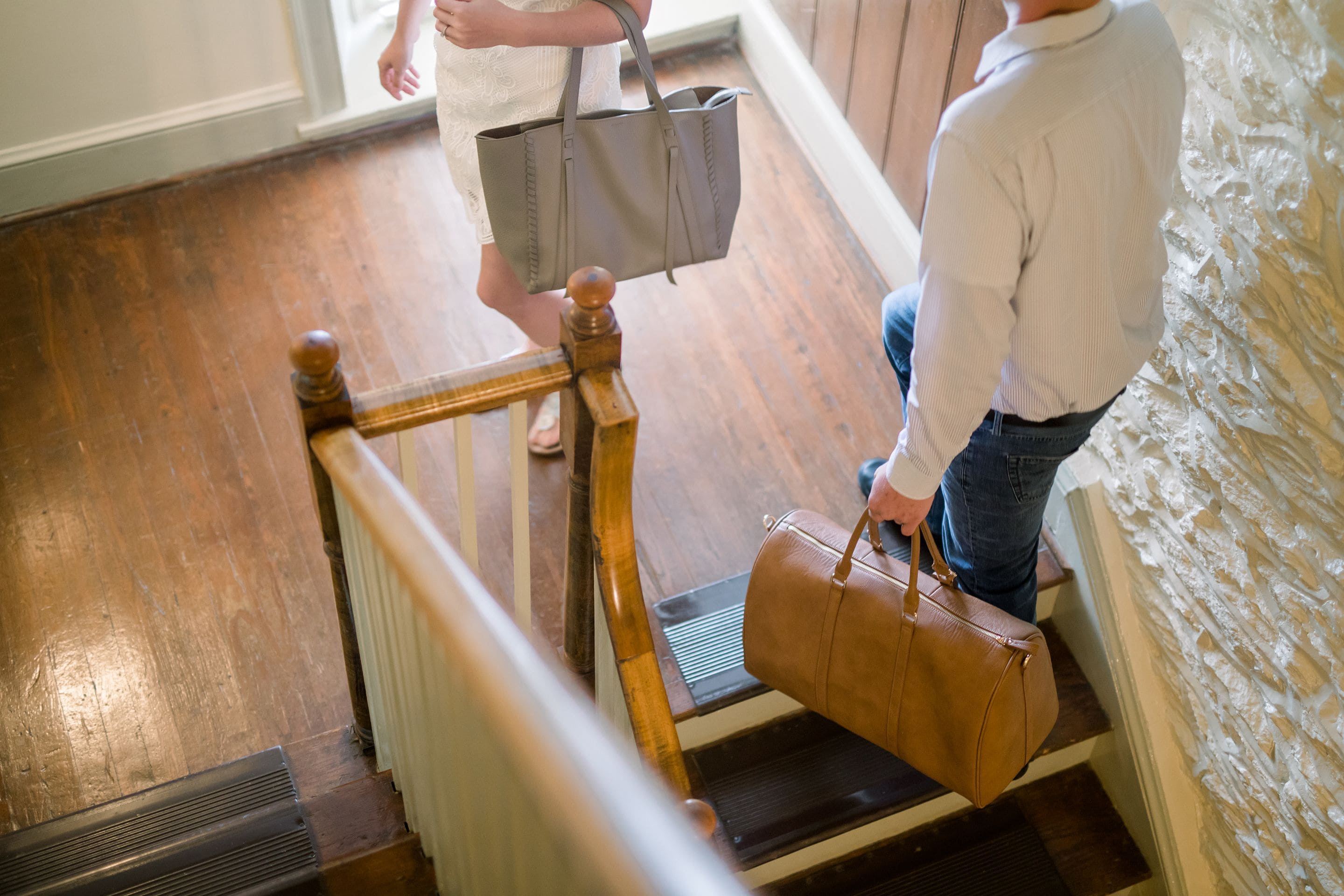 A wooden staircase with a handrail, a person descending, and another ascending.