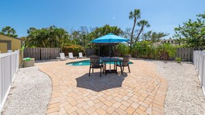 A backyard with a pool, patio furniture, and a pergola with a blue umbrella. - AMI North End Private Heated Pool.  1.2 Block to Gulf Beach! (Anna Maria)